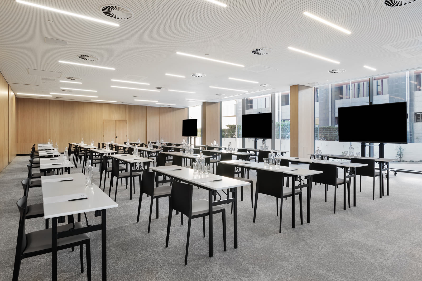 Sala Mini-Lab do Moxy Alfragide, em formato escola com mesas e ecrãs